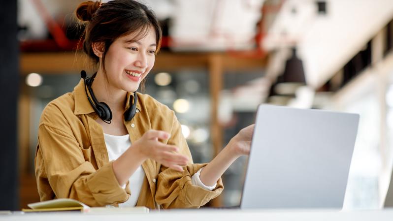 Asian woman smiling actively taking an instructor-lead online training course
