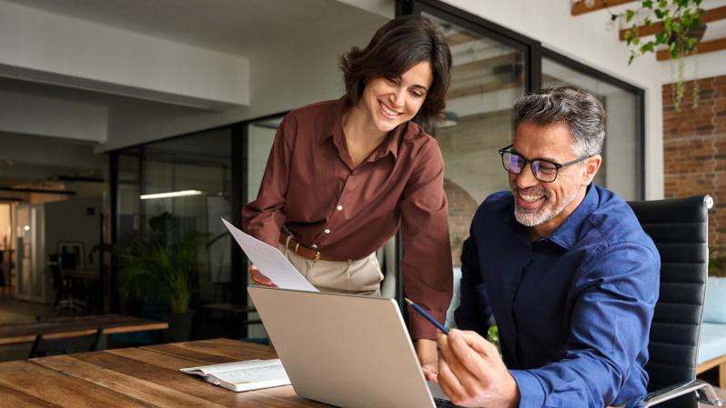 Man and woman working together at a laptop in a modern office