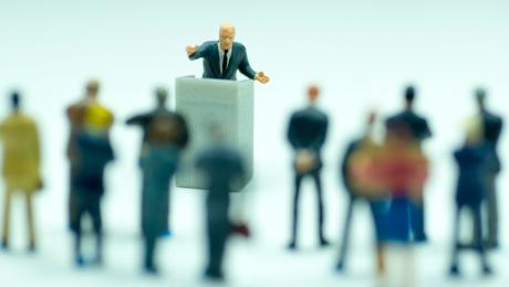 Figurines of a man speaking from a podium with audience